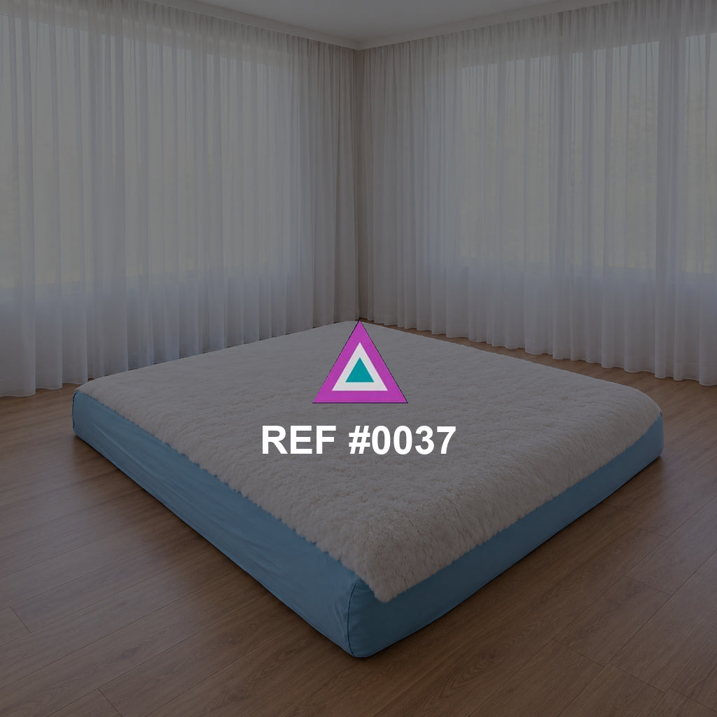 Sueño a Ras del Suelo. Una cama baja de base azul y ropa blanca en un interior de grandes cortinas claras.