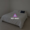 Marfil en Reposo. Una cama de ropa clara en un dormitorio sencillo, con un cojín azul como acento.