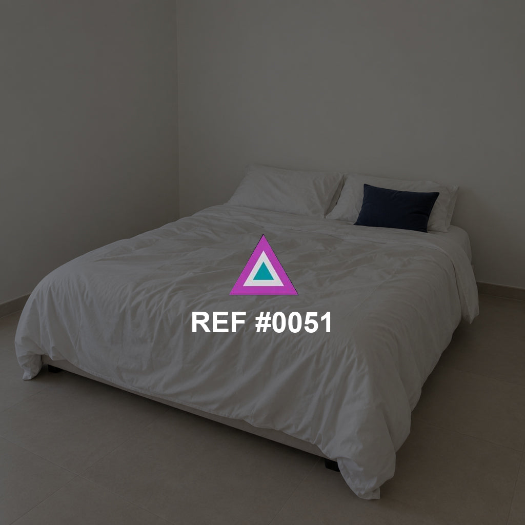 Marfil en Reposo. Una cama de ropa clara en un dormitorio sencillo, con un cojín azul como acento.