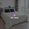 Luz entre Visillos. Una cama blanca con cojines azules junto a cortinas translúcidas y una planta.