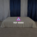 Refugio de Pliegues. Una cama baja de tela marfil frente a cortinas azules y blancas.