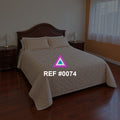 Madera y Memoria. Una cama de cabecera tallada y ropa beige sobre un piso de madera oscura.