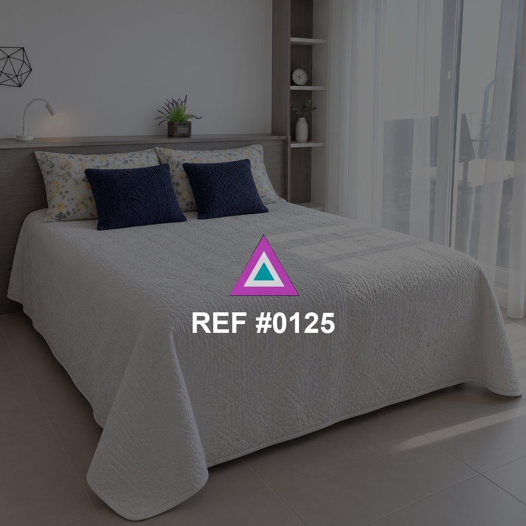 Luz entre Visillos. Una cama blanca con cojines azules junto a cortinas translúcidas y una planta.