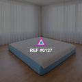 Sueño a Ras del Suelo. Una cama baja de base azul y ropa blanca en un interior de grandes cortinas claras.