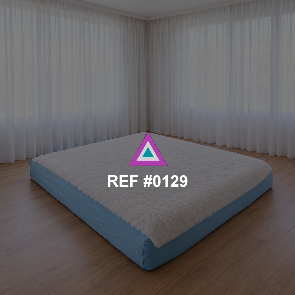 Sueño a Ras del Suelo. Una cama baja de base azul y ropa blanca en un interior de grandes cortinas claras.