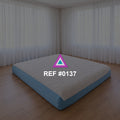 Sueño a Ras del Suelo. Una cama baja de base azul y ropa blanca en un interior de grandes cortinas claras.