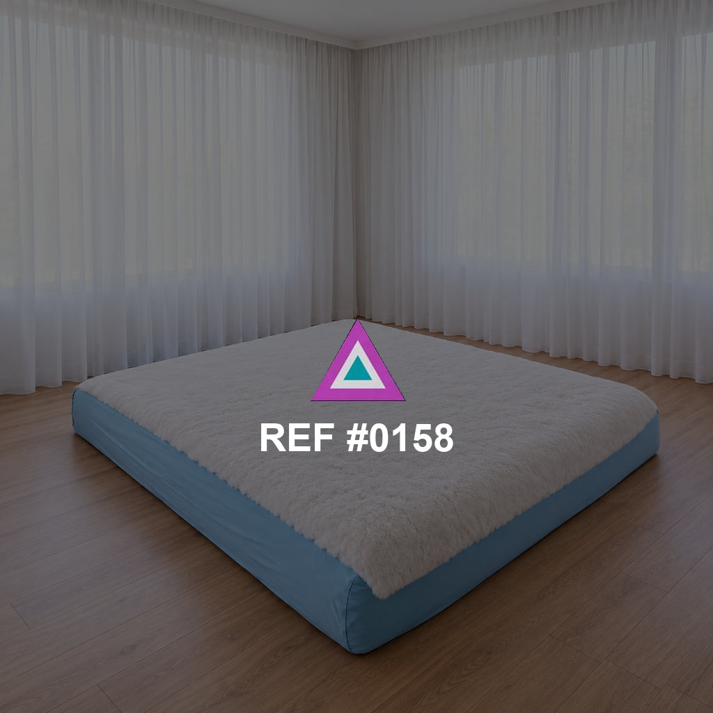 Sueño a Ras del Suelo. Una cama baja de base azul y ropa blanca en un interior de grandes cortinas claras.