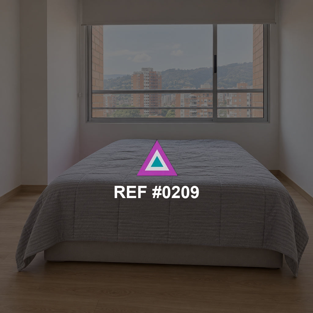 Ciudad en Reposo. Una cama gris junto a una ventana amplia que muestra edificios de la ciudad.