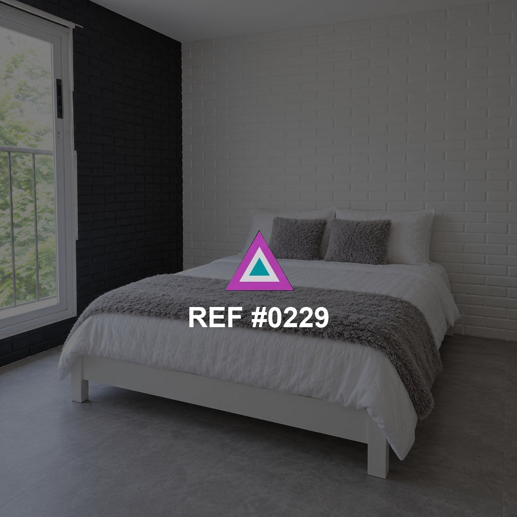 Blanco sobre Ladrillo. Una cama en tonos blanco y gris junto a una pared de ladrillo pintado y una ventana lateral.