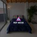 Calma Azul. Una cama azul profundo bajo un techo de madera, acompañada por plantas y un gran ventanal.