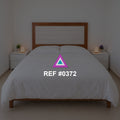Luz sobre Rosado. Una cama rosada de cabecera de madera entre pequeños muebles claros.